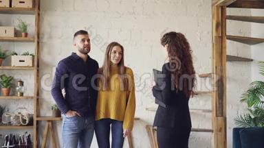一对漂亮的夫妇正在和站在漂亮房子里的女房地产经纪人讨论房地产交易